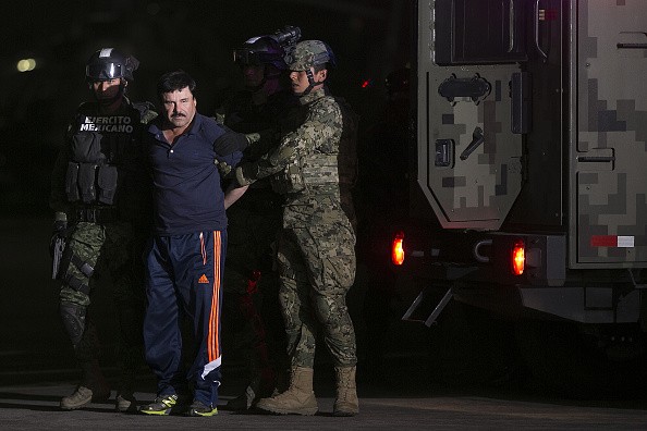 Joaquin Guzman, the world's most wanted-drug trafficker, second left, is escorted by Mexican security forces at a Navy hangar in Mexico City, Mexico, on Friday, Jan. 8, 2016. 