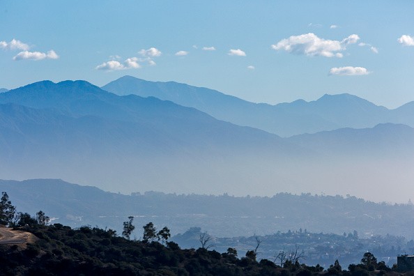 The San Gabriel mountains above Los Angeles with an inversion layer of dirty air, smog. SB 350 signed in to law. California Governor Jerry Brown signing SB 350, the climate and clean energy legislation bill.