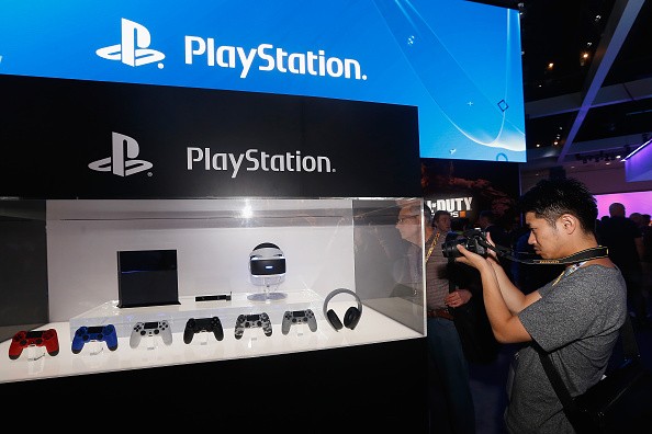 A game enthusiast takes photos of the Sony PlayStation 4 and peripherals.