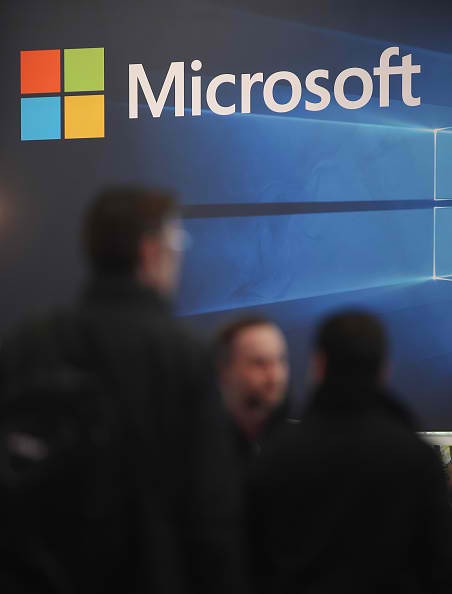 People walk past the Microsoft stand at the 2016 CeBIT digital technology trade fair on the fair's opening day on March 14, 2016 in Hanover, Germany.