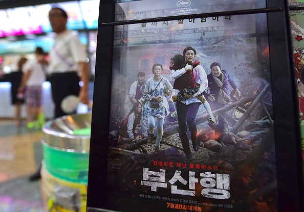 A man walks past a poster of the first South Korean zombie blockbuster, entitled 'Train to Busan', at a movie theater in Seoul on August 4, 2016. The film depicts a group of people trying to survive a mysterious virus by boarding an express train bound fo