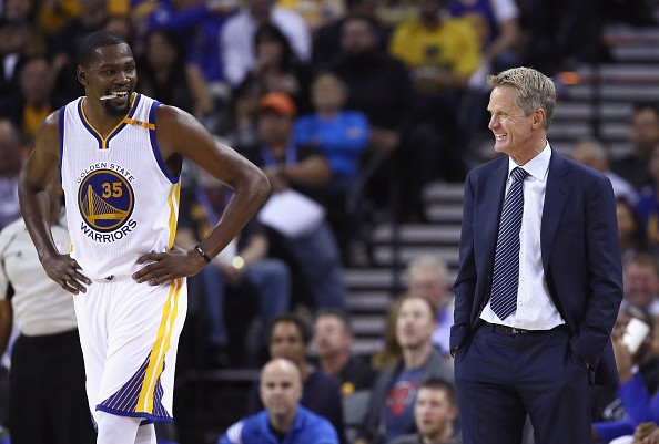 Head coach Steve Kerr of the Golden State Warriors talks to Kevin Durant during their preseason game against the Los Angeles Clippers at ORACLE Arena on October 4, 2016 in Oakland, California. 