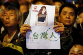 A supporter of Tsai Ing-wen holds up a poster of Taiwanese K-pop singer Chou Tzuyu at their party headquarters.