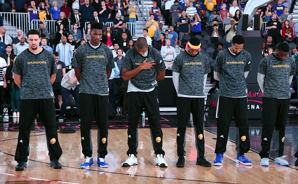 Members of the Golden State Warriors stand on the court as the American national anthem is performed before their preseason game against the Los Angeles Lakers at T-Mobile Arena on October 15, 2016 in Las Vegas, Nevada. Golden State won 112-107. 
