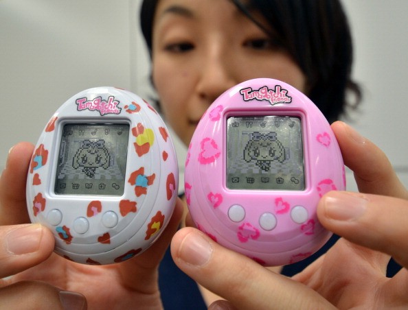 This picture taken on November 27, 2013 shows Japanese toy giant Bandai employee Tomomi Washizu displaying the new Tamagotchi virtual pet toy release 'Tamagotchi Friends', an egg-shaped portable toy featuring cartoonlike characters, at the company's headq