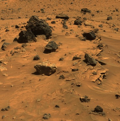 True-colour image of Martian rocks in the Gusev Crater. Three types of rocks are seen here: thin, jagged rocks buried under the sand; light grey, rounded rocks; and dark, pockmarked rocks. The dark rocks are thought to be volcanic in origin. This image wa