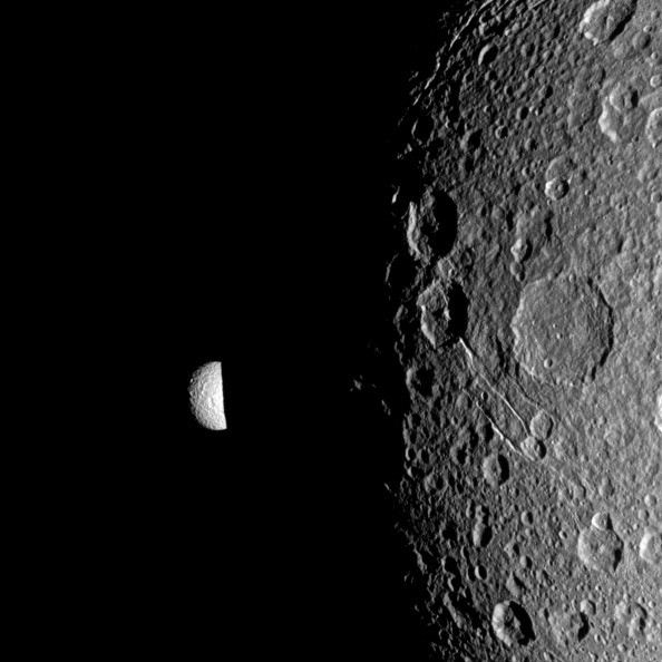 Saturn's moon Mimas peeks out from behind the night side of the larger moon Dione in this Cassini image. 