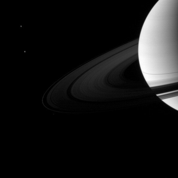 A pair of Saturn's moons accompany the planet and its rings. Dione is in top left and Tethys is below. Cassini. 