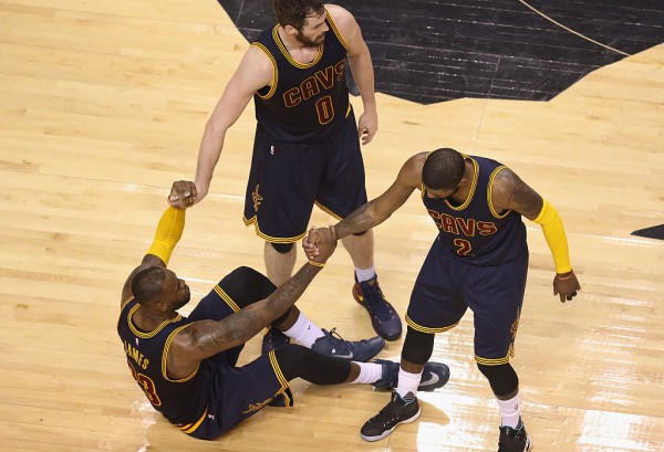 Kevin Love (middle) and Kyrie Irving help LeBron James get up.