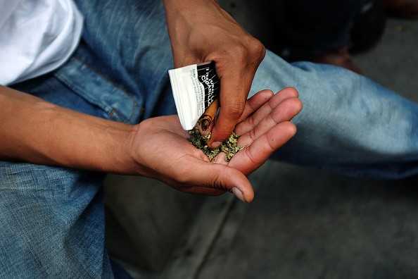A man prepares to smoke K2 or 'Spice', a synthetic marijuana drug, along a street in East Harlem on August 5, 2015 in New York City.