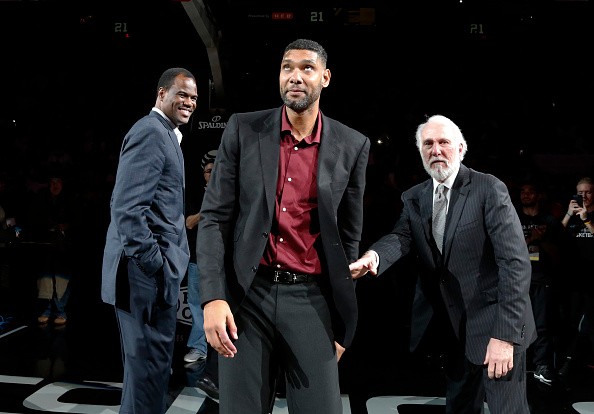 Former San Antonio Spurs star Tim Duncan (C) reacts to the crowd as head coach Gregg Popovich (R) and former Spur David Robinson (L) look on while honoring the retirement of Duncan's jersey number at AT&T Center after the game against the New Orleans Peli