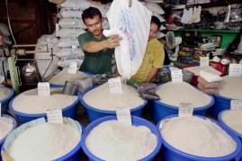  A rice vendor pours a sack of rice into a plastic container for sale at a market in Jakarta, 13 August 2002
