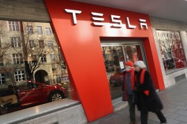 A couple, who said they did not mind being photographed, walk past a Tesla car dealership on December 9, 2016 in Munich, Germany. Tesla has established itself firmly on the German market.