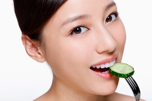 The image features the woman eating pickles as a means to maintaining her glow naturally.  