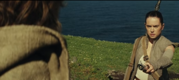 Rey hands Luke Skywalker his lightsaber in a scene from "Star Wars: The Last Jedi."