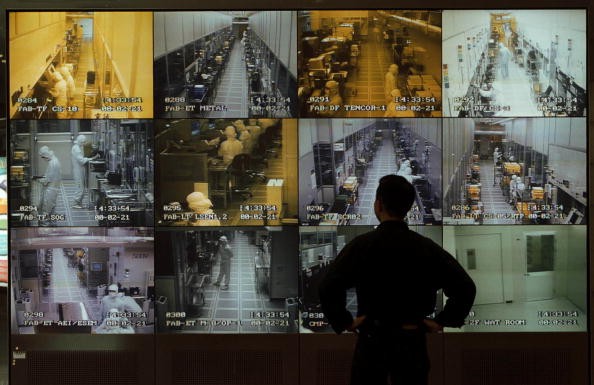 A visitor to United Manufacturing Corporation observes semiconductor manufacturing on wall of monitors in the company's reception area, Hsinchu, Taiwan, May 1, 2000. 