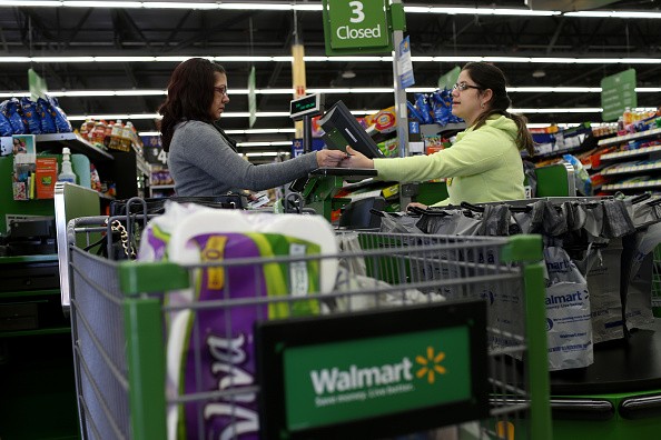 Walmart employee Adriana Cajuso (R) takes payment from customer Yoalmi Matias as she checks-out at a Walmart store on February 19, 2015 in Miami, Florida. 